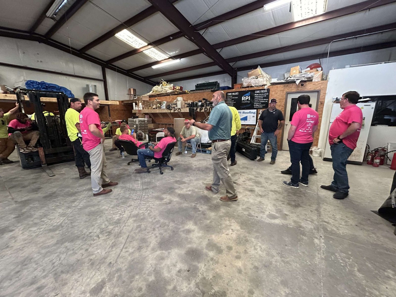 The RPI Roofing crew gathered for a huddle inside the shop during National Roofing Week